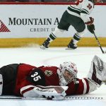 Arizona Coyotes goaltender Darcy Kuemper (35) grimaces in pain as Minnesota Wild right wing Ryan Hartman (38) skates past during the third period of an NHL hockey game Thursday, Dec. 19, 2019, in Glendale, Ariz. Kuemper left the game, which the Wild won 8-5. (AP Photo/Ross D. Franklin)