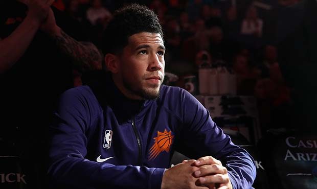 Devin Booker #1 of the Phoenix Suns sits on the bench before the start of the NBA game against the ...