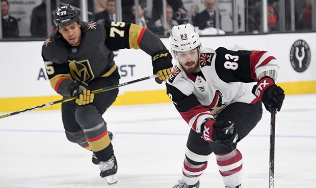 Conor Garland #83 of the Arizona Coyotes skates with the puck against Ryan Reaves #75 of the Vegas ...