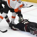 Arizona Coyotes goalie Antti Raanta (32) falls on the puck as Philadelphia Flyers' James van Riemsdyk (25) fights for it while Coyotes' Alex Goligoski (33) watches during the second period of an NHL hockey game Saturday, Jan. 4, 2020, in Glendale, Ariz. (AP Photo/Darryl Webb)