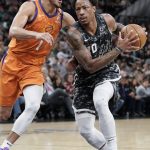 San Antonio Spurs' DeMar DeRozan, right, drives against Phoenix Suns' Devin Booker during the first half of an NBA basketball game, Friday, Jan. 24, 2020, in San Antonio. (AP Photo/Darren Abate)