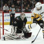 Arizona Coyotes goaltender Adin Hill (31) makes a save on a shot as Pittsburgh Penguins right wing Bryan Rust (17) gets out of the way of the shot during the second period of an NHL hockey game Sunday, Jan. 12, 2020, in Glendale, Ariz. (AP Photo/Ross D. Franklin)
