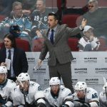 San Jose Sharks interim head coach Bob Boughner, middle, stands on the bench to wave his goalie off the ice as assistant coach Mike Ricci, back left, looks at the action on the ice during the third period of an NHL hockey game against the Arizona Coyotes Tuesday, Jan. 14, 2020, in Glendale, Ariz. The Coyotes defeated the Sharks 6-3. (AP Photo/Ross D. Franklin)