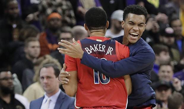Arizona guard Jemarl Baker Jr. (10) is hugged by a teammate at the end of an NCAA college basketbal...