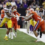 Clemson linebacker Isaiah Simmons pulls off a piece of tape on LSU wide receiver Ja'Marr Chase during the second half of a NCAA College Football Playoff national championship game Monday, Jan. 13, 2020, in New Orleans. (AP Photo/Sue Ogrocki)