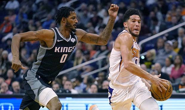 Phoenix Suns guard Devin Booker (1) runs past Sacramento Kings forward Trevor Ariza during the seco...