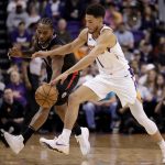 Phoenix Suns guard Devin Booker, right, and Los Angeles Clippers guard Reggie Jackson chase down a lose ball during the first half of an NBA basketball game, Wednesday, Feb. 26, 2020, in Phoenix. (AP Photo/Matt York)