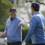Phil Mickelson is greeted by Steve Young after chipping the ball into the 14th hole of the Pebble Beach Golf Links for a birdie during the third round of the AT&T Pebble Beach National Pro-Am golf tournament Saturday, Feb. 8, 2020, in Pebble Beach, Calif. (AP Photo/Eric Risberg)