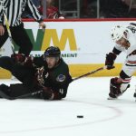 Arizona Coyotes defenseman Niklas Hjalmarsson (4) and Chicago Blackhawks center Zack Smith (15) become entangled as they go for the puck during the third period of an NHL hockey game Saturday, Feb. 1, 2020, in Glendale, Ariz. (AP Photo/Ross D. Franklin)