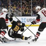 Boston Bruins' Brad Marchand is dumped in front of the net by Arizona Coyotes' Christian Dvorak (18) and Jordan Oesterle during the first period of an NHL hockey game Saturday, Feb. 8, 2020, in Boston. (AP Photo/Winslow Townson)