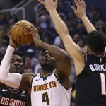 Denver Nuggets forward Paul Millsap (4) drives to the basket between the defense of Phoenix Suns' Deandre Ayton, left, and Devin Booker (1) during the first half of an NBA basketball game, Saturday, Feb. 8, 2020, in Phoenix. (AP Photo/Ralph Freso)