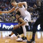 Phoenix Suns guard Devin Booker, left, falls back into the defense of Denver Nuggets center Nikola Jokic (15) as he looks to pass the ball during the first half of an NBA basketball game, Saturday, Feb. 8, 2020, in Phoenix. (AP Photo/Ralph Freso)