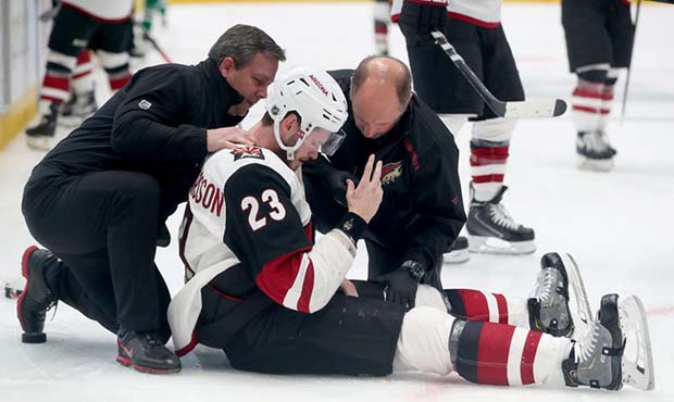 Oliver Ekman-Larsson #23 of the Arizona Coyotes is checked out by team attendants after being check...