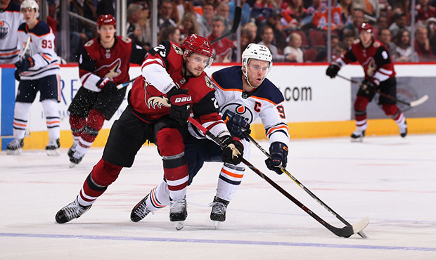 Oliver Ekman-Larsson #23 of the Arizona Coyotes and Connor McDavid #97 of the Edmonton Oilers skate...