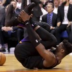 Phoenix Suns center Deandre Ayton grabs his foot after being injured during the second half of an NBA basketball game against the Toronto Raptors Tuesday, March 3, 2020, in Phoenix. The Raptors won 123-114. (AP Photo/Matt York)