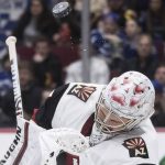 The puck deflects off Arizona Coyotes goalie Darcy Kuemper's mask during the second period of the team's NHL hockey game against the Vancouver Canucks on Wednesday, March 4, 2020, in Vancouver, British Columbia. (Darryl Dyck/The Canadian Press via AP)