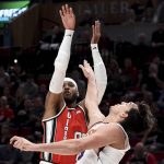Portland Trail Blazers forward Carmelo Anthony, left, hits a shot over Phoenix Suns forward Dario Saric during the first quarter of an NBA basketball game in Portland, Ore., Tuesday, March 10, 2020. (AP Photo/Steve Dykes)