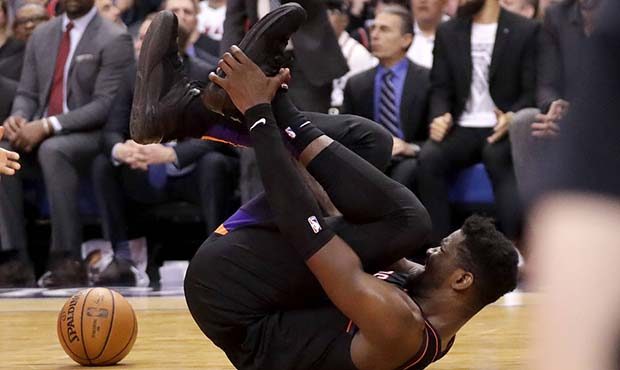 Phoenix Suns center Deandre Ayton grabs his foot after being injured during the second half of an N...