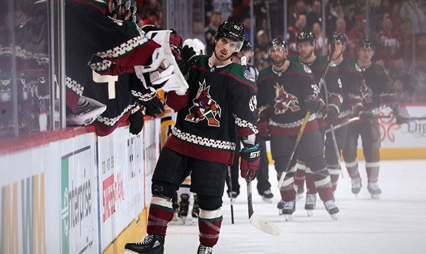 Conor Garland #83 of the Arizona Coyotes celebrates with teammates on the bench after scoring a goa...