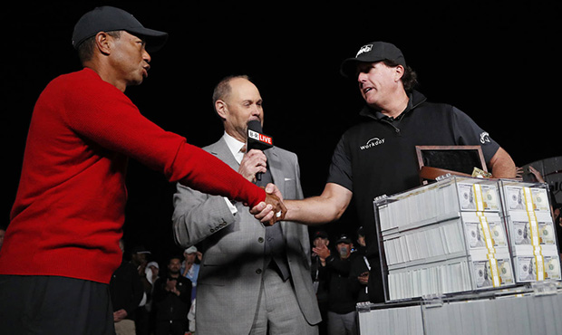 Tiger Woods, left, shakes hands after losing a a golf match to Phil Mickelson, right, at Shadow Cre...