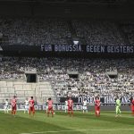 The players hold a minute of silence on the pitch ahead the German first division Bundesliga football match Borussia Moenchengladbach and Bayer 04 Leverkusen on Saturday, May 23, 2020 in Moenchengladbach, western Germany. (Ina Fassbender/pool via AP)