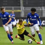 Dortmund's Thorgan Hazard falls down between Schalke's Matija Nastasic, left, and Weston McKennie during the German Bundesliga soccer match between Borussia Dortmund and Schalke 04 in Dortmund, Germany, Saturday, May 16, 2020. The German Bundesliga becomes the world's first major soccer league to resume after a two-month suspension because of the coronavirus pandemic. (AP Photo/Martin Meissner, Pool)