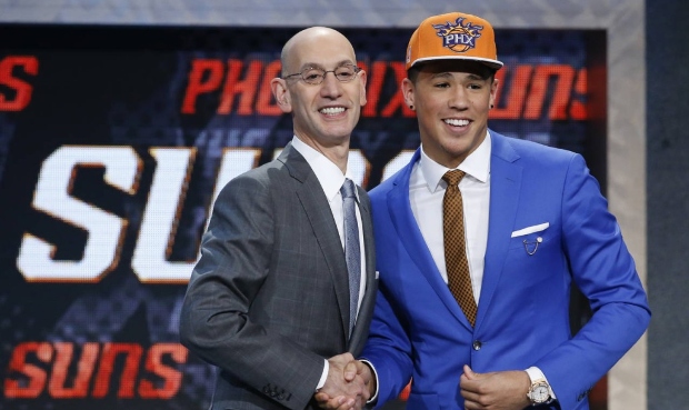 Devin Booker poses for photos with NBA Commissioner Adam Silver after being selected 13th overall b...