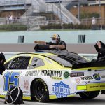 Crew members cover the car of Brennan Poole (15) during a weather delay at a NASCAR Cup Series auto race Sunday, June 14, 2020, in Homestead, Fla. (AP Photo/Wilfredo Lee)