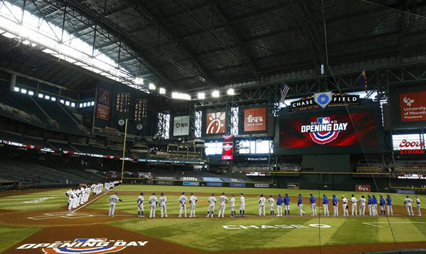 Arizona Diamondbacks players and coaches, left, stand along with Los Angeles Dodgers players and co...