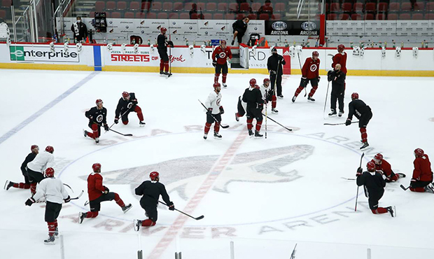 Arizona Coyotes players and coaches pause on the ice during NHL hockey practice at Gila River Arena...