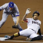 Arizona Diamondbacks' Ketel Marte (4) is tagged out at third base trying to stretch a double into a triple by Los Angeles Dodgers shortstop Corey Seager, left, during the first inning of a baseball game Friday, July 31, 2020, in Phoenix. (AP Photo/Ross D. Franklin)