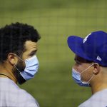 With face coverings on, Los Angeles Dodgers' Edwin Rios, left, and Joc Pederson talk in the dugout during the sixth inning of the team's baseball game against the Arizona Diamondbacks, who were playing their home-opener, Thursday, July 30, 2020, in Phoenix. (AP Photo/Ross D. Franklin)