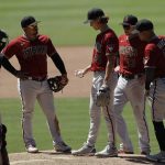 Arizona Diamondbacks starting pitcher Luke Weaver, middle, meets players on the mound before leaving during the fourth inning of the team's baseball game against the San Diego Padres, Monday, July 27, 2020, in San Diego. (AP Photo/Gregory Bull)