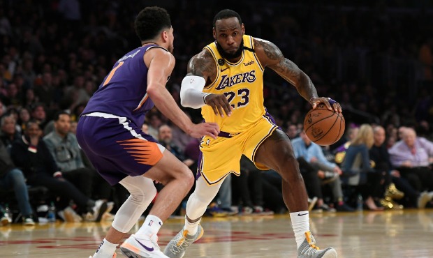 LeBron James #23 of the Los Angeles Lakers drives against Devin Booker #1 of the Phoenix Suns durin...