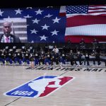 The Philadelphia 76ers, left, and Pheonix Suns NBA basketball teams kneel during the National Anthem prior to the start of an NBA basketball game Tuesday, Aug. 11, 2020, in Lake Buena Vista, Fla. (AP Photo/Ashley Landis, Pool)