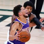 Phoenix Suns' Devin Booker draws a foul from Los Angeles Clippers' Paul George, rear, during an NBA basketball game Tuesday, Aug. 4, 2020, in Lake Buena Vista, Fla. (Kevin C. Cox/Pool Photo via AP)