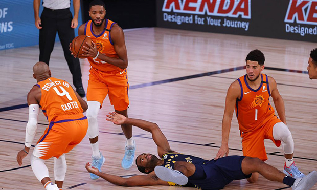 Phoenix Suns' Mikal Bridges (25) picks up the ball as Indiana Pacers' T.J. Warren, center bottom, g...