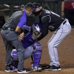 Colorado Rockies catcher Tony Wolters is helped up by manager Bud Black and the team trainer after being injured during the ninth inning of a baseball game against the Arizona Diamondbacks, Monday, Aug. 24, 2020, in Phoenix. Wolters left the game. (AP Photo/Matt York)