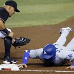Los Angeles Dodgers' A.J. Pollock, right, dives safely back to first base as Arizona Diamondbacks first baseman Ildemaro Vargas, left, reaches to apply a late tag during the second inning of a baseball game Saturday, Aug. 1, 2020, in Phoenix. (AP Photo/Ross D. Franklin)