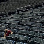 A grounds crew member sits in the stands prior to a baseball game between the Colorado Rockies and the Arizona Diamondbacks, Wednesday, Aug. 26, 2020, in Phoenix. (AP Photo/Matt York)