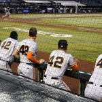 San Francisco Giants players watch from the dugout in the fifth inning during a baseball game against the Arizona Diamondbacks, Saturday, Aug 29, 2020, in Phoenix. Players from both teams wore No. 42 on their jerseys in honor of baseball great Jackie Robinson. (AP Photo/Rick Scuteri)
