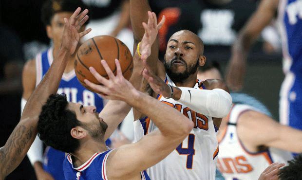 Philadelphia 76ers guard Furkan Korkmaz, left, takes a shot as Phoenix Suns guard Jevon Carter (4) ...