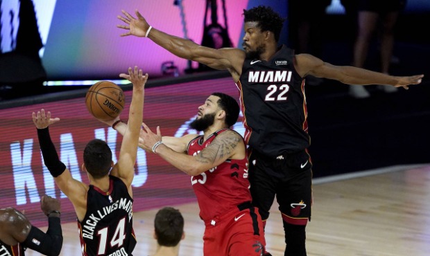 Toronto Raptors' Fred VanVleet shoots between Miami Heat's Jimmy Butler (22) and Tyler Herro (14) d...