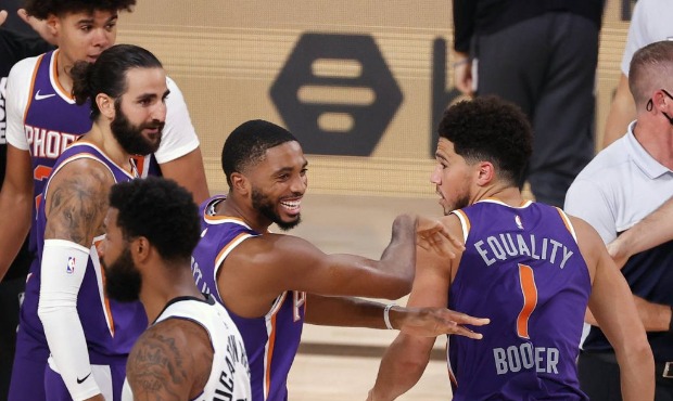 Phoenix Suns' Devin Booker (1) celebrates with teammate Mikal Bridges after scoring the game winnin...