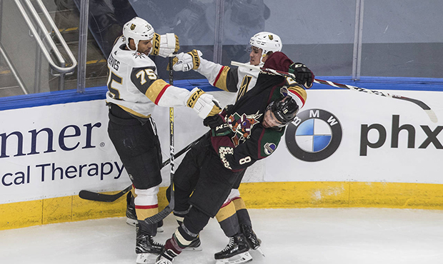 Arizona Coyotes' Nick Schmaltz (8) is checked by Vegas Golden Knights' Ryan Reaves (75) and Zach Wh...