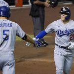 Los Angeles Dodgers' Enrique Hernandez, right, wearing Pittsburgh Pirates Hall of Fame player Roberto Clemente's No. 21 on Roberto Clemente Day, celebrates his home run against the Arizona Diamondbacks with Corey Seager (5) during the second inning of a baseball game Wednesday, Sept. 9, 2020, in Phoenix. (AP Photo/Ross D. Franklin)