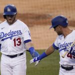 Los Angeles Dodgers' Max Muncy, left, almost shakes hands with Matt Beaty after Muncy scored on a single by Chris Taylor during the first inning of the team's baseball game against the Arizona Diamondbacks on Thursday, Sept. 3, 2020, in Los Angeles. (AP Photo/Marcio Jose Sanchez)