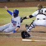 Los Angeles Dodgers' A.J. Pollock scores on a base hit by teammate Chris Taylor as Arizona Diamondbacks' catcher Daulton Varsho makes the late tag during the 10th inning of a baseball game, Tuesday, Sept. 8, 2020, in Phoenix. (AP Photo/Matt York)