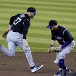 Colorado Rockies shortstop Trevor Story (27) makes a fielding error on a grounder hit by Arizona Diamondbacks' Josh VanMeter as Rockies second baseman Garrett Hampson, right, runs past Story during the first inning during the second game of a baseball doubleheader Friday, Sept. 25, 2020, in Phoenix. (AP Photo/Ross D. Franklin)