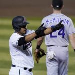 Arizona Diamondbacks' Eduardo Escobar points to the dugout as he stands at third after his RBI triple, while Colorado Rockies third baseman Ryan McMahon looks for the baseball during the third inning during the first game of a doubleheader Friday, Sept. 25, 2020, in Phoenix. (AP Photo/Ross D. Franklin)